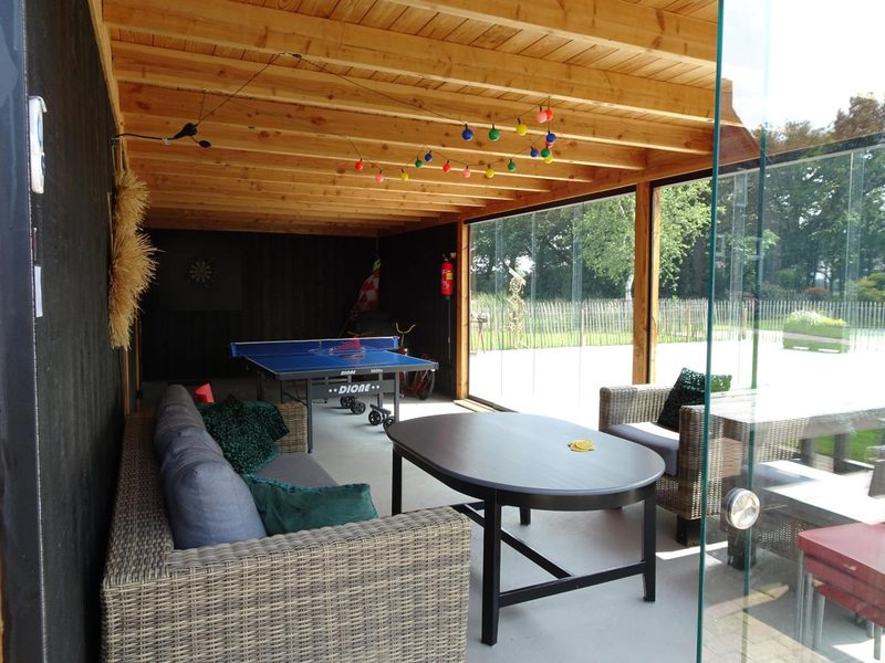 De overdekte veranda met tafeltennistafel en loungebank
